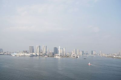 Sea by modern buildings against sky