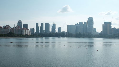 Sea and buildings in city against sky