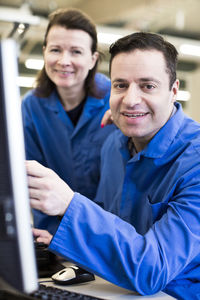 Portrait of confident technicians with computer at desk in industry