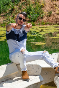 Full length of smiling young man holding sunglasses