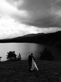 Full length of couple on land by lake against sky