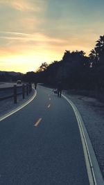 Silhouette of person walking on road against sky during sunset