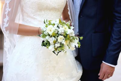 Midsection of couple holding bouquet