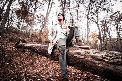 Man sitting on fallen tree in forest