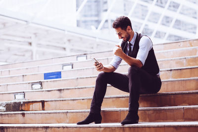 Young man using mobile phone while sitting on staircase