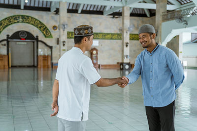 Smiling men shaking hands in mosque