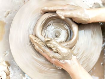 Cropped hands of person molding shape on pottery wheel