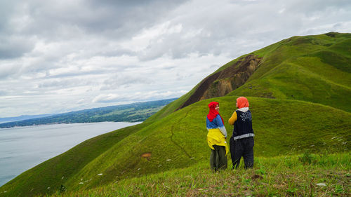 Woman with umbrella on mountain against sky