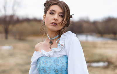 Portrait of young woman standing against sky