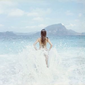 Rear view of man surfing in sea against sky