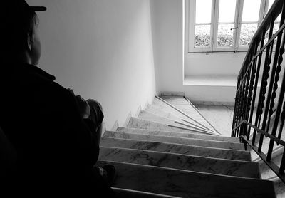 Rear view of man sitting by window at home