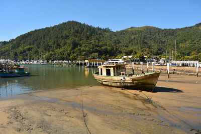 Boat moored on beach against clear sky