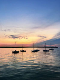 Silhouette sailboats in sea against sky during sunset