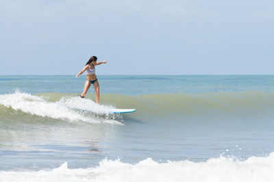 Young woman surfboarding in sea