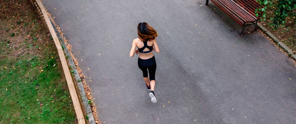 Rear view of woman running on road