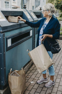 Woman putting cardboard in recycling bin