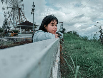 Portrait of young woman looking at camera against sky