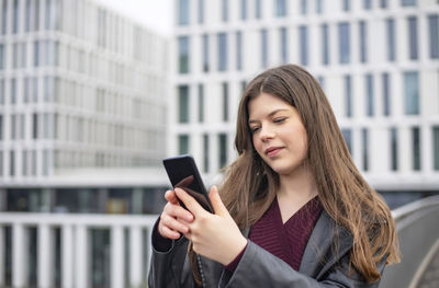 Young woman using mobile phone in city