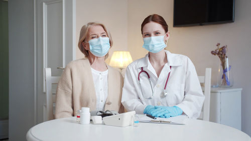 Doctor and patient wearing protective face mask at home