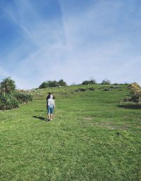 Rear view of man walking on field against sky