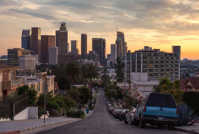 Street amidst buildings against sky during sunset