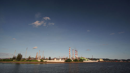 View of factory by sea against sky