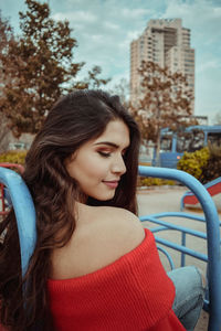 Beautiful young woman sitting on outdoor play equipment at playground