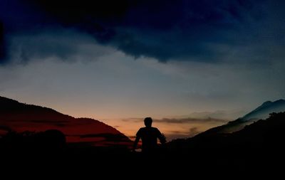 Silhouette man looking at mountains against sky during sunset