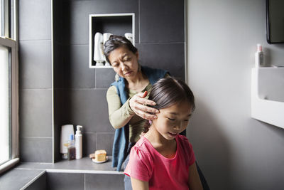 Mother grooming daughter in bathroom