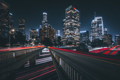 Illuminated modern buildings in city against sky at night