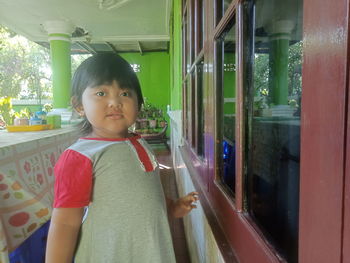 Portrait of cute girl looking through window