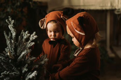 Toddler baby girl in rudolph reindeer costumes decorating christmas tree christmas tree