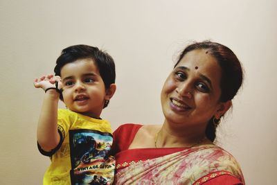 Portrait of smiling woman with son against wall