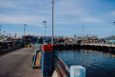 Sailboats moored on pier at harbor against sky