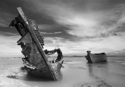 Abandoned boat on beach against sky