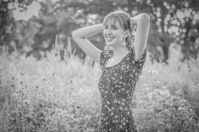 Portrait of smiling young woman standing at field