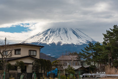 Houses by snowcapped mountains against sky