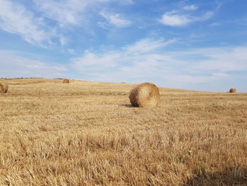 Hay bales on field against sky