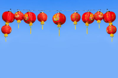 Low angle view of lanterns hanging against clear blue sky