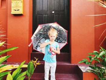 Full length of a smiling girl standing against built structure