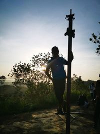 Rear view of silhouette man standing on street against sky during sunset