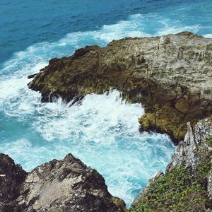 Aerial view of blue sea waves crashing on rock coastline