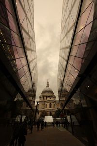 People in alley amidst glass buildings against st paul cathedral