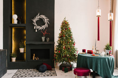 Stylish luxurious interior of the dining room with a christmas tree. a chair near a round table