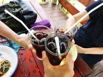 Cropped hands of friends toasting cold drinks at restaurant