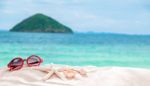 Close-up of sunglasses on beach against sky