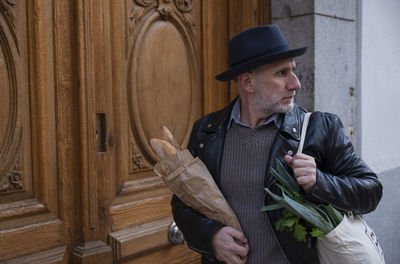 Adult man in hat holding bread and vegetable bag on street. madrid, spain