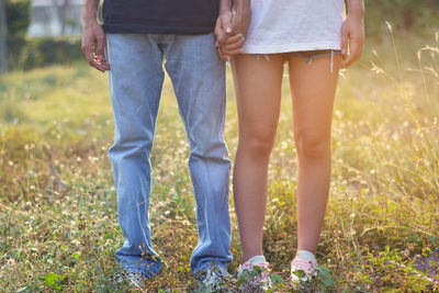 Low section of friends standing on field