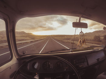 Road seen through car windshield during sunset