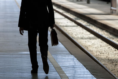 Low section of woman walking on railroad track